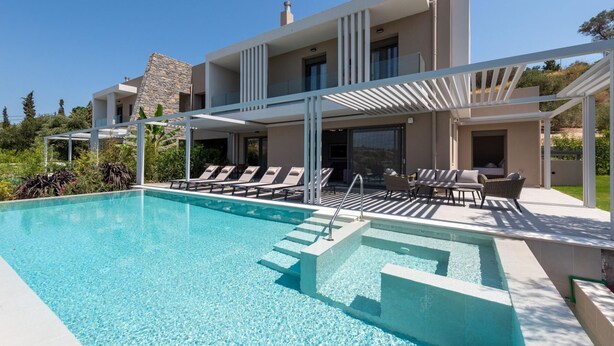 Una casa moderna de dos pisos con piscina, mobiliario exterior y fachada de piedra.