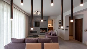 Una sala de estar moderna con un sofá, un televisor y lámparas colgantes.