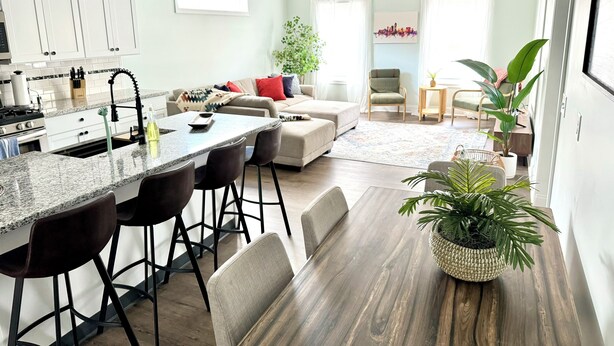 A modern kitchen with a central island, bar stools, and a dining table. There is a living area with a sofa and a coffee table. - Heart of Convenience Downtown near Convention Center-Lucas Oil-Fully Remodeled  (Indianapolis)