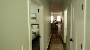 A narrow hallway with a bed on the left, a kitchen area in the center, and a door on the right. - Heart of Convenience Downtown near Convention Center-Lucas Oil-Fully Remodeled  (Indianapolis)