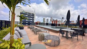 A rooftop terrace with outdoor seating, a pool, and a cityscape view. - AX Way Tambaú Suítes (João Pessoa)