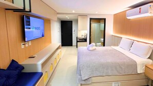 A hotel room with a bed, a TV mounted on the wall, a desk, and a seating area. - AX Way Tambaú Suítes (João Pessoa)