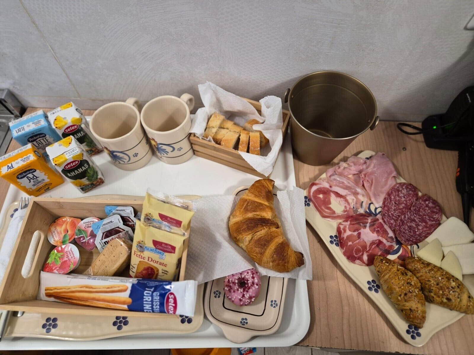 A breakfast tray with croissants, pastries, cheese, and cured meats.