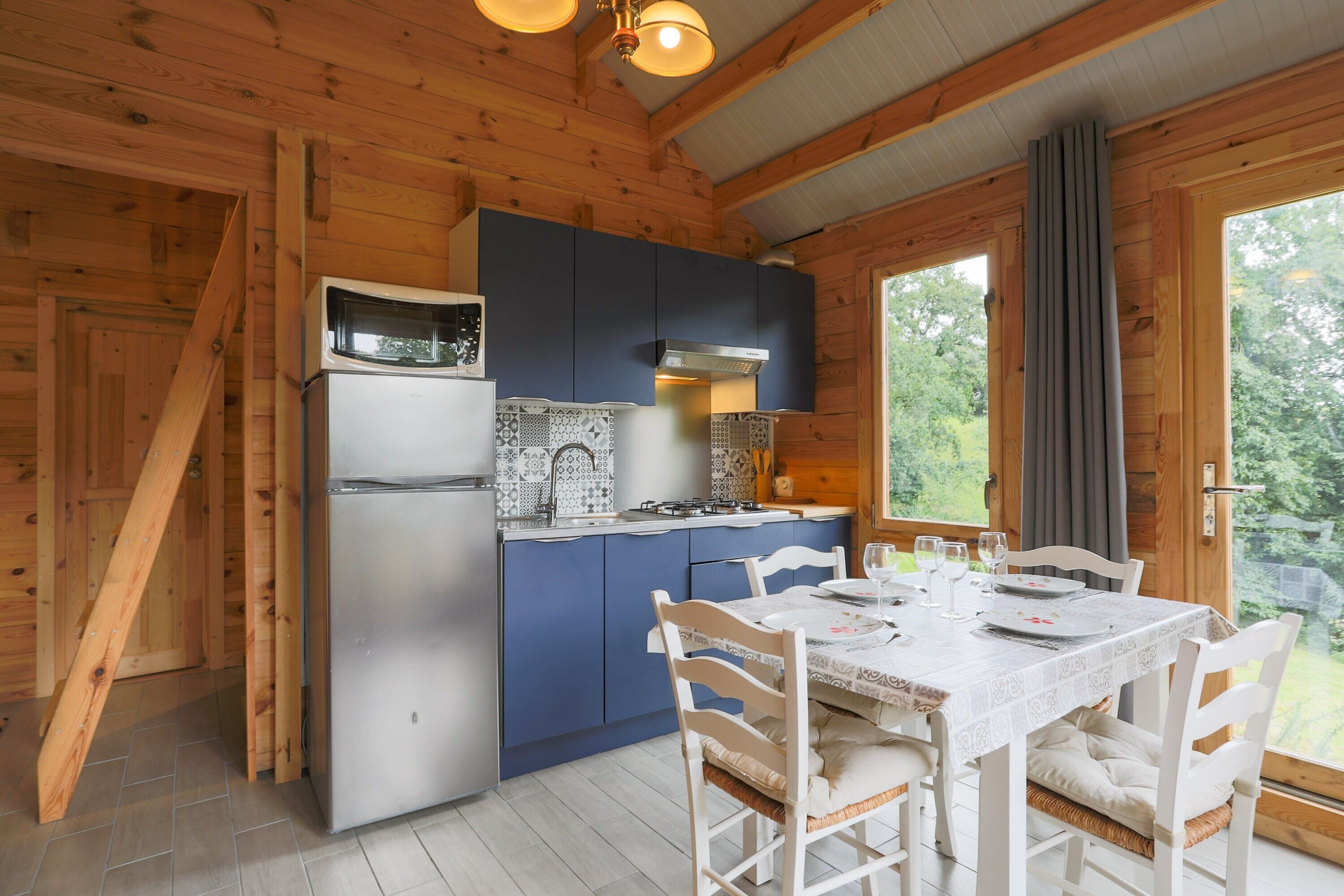 A wooden cabin kitchen with a refrigerator, stove, and blue cabinets.