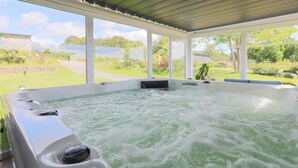 Un jacuzzi con vistas a un jardín y un edificio al fondo.