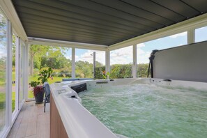 Un jacuzzi con vistas a un jardín y un patio cubierto.