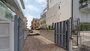 Un cancello d'ingresso conduce a un edificio residenziale, con un vialetto lastricato che vi porta.