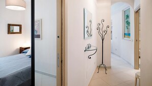 Un corridoio con un letto, uno specchio e un quadro appeso al muro.