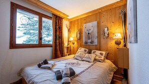 A wooden-paneled bedroom with a bed, two bedside lamps, a large window, and a wall-mounted ski rack. - Apartment 'Le Châtelard' with Mountain View, Private Terrace and Wi-Fi (Val-d'Isère)