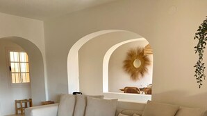 Een moderne woonkamer met een beige bank, een bijzettafeltje en een decoratieve spiegel.