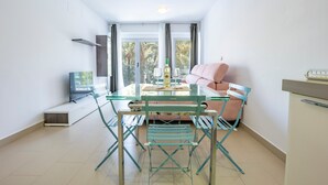 A modern living room with a glass table, teal chairs, a pink sofa, and a TV on a stand. - Apartment 'Playa De Poniente' with Sea View, Wi-Fi and Air Conditioning (Benidorm)