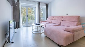 A modern living room with a pink sofa, a flat-screen TV, and a small round table. - Apartment 'Playa De Poniente' with Sea View, Wi-Fi and Air Conditioning (Benidorm)