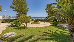 A landscaped garden with palm trees, a circular flower bed, and a view of the sea. - Apartment 'Playa De Poniente' with Sea View, Wi-Fi and Air Conditioning (Benidorm)