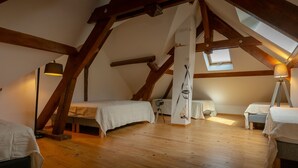 Ein Zimmer mit hohen Decken, Holzbalken, zwei Betten, einem Tisch und einer Hängelampe.