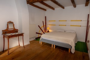 A bedroom with a wooden bed, a small table with a mirror, and a radiator.