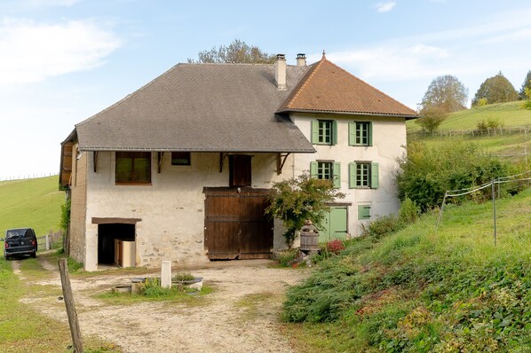 A two-story house with a dirt driveway and a wooden gate.