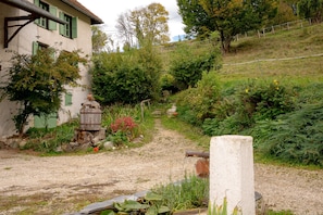 A rural setting with a gravel path, a wooden barrel, and a stone well.
