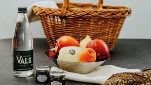 A bottle of Vals wine, a wicker basket with fruits, and a loaf of bread on a table. - Holiday Home 'Gite Villa T1' with Shared Pool, Wi-Fi and Air Conditioning (Vals-les-Bains)