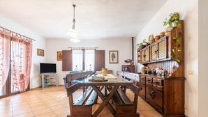 A dining area with a wooden table and benches, a television on a stand, and a cabinet with decorative items. - Villa 'Oliveto' with Mountain View, Private Terrace and Air Conditioning (Villa san pietro)
