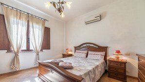 A bedroom with a wooden bed, two bedside tables with lamps, a wardrobe, and a window with curtains. - Villa 'Oliveto' with Mountain View, Private Terrace and Air Conditioning (Villa san pietro)