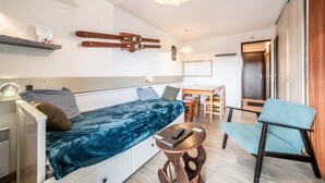 Een kleine kamer met een bed, een tafel, een stoel en een plafondlamp.