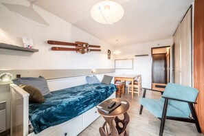 Una habitación pequeña con cama, mesa, silla y lámpara en el techo.