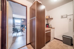 Une cuisine de taille réduite comprenant un réfrigérateur, un petit plan de travail et une poubelle.