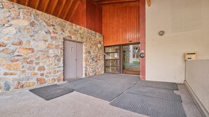 A stone exterior wall, a wooden ceiling, and a door leading to an interior space. - Apartment 'Appartement Alpe D'huez' with Balcony (Huez)