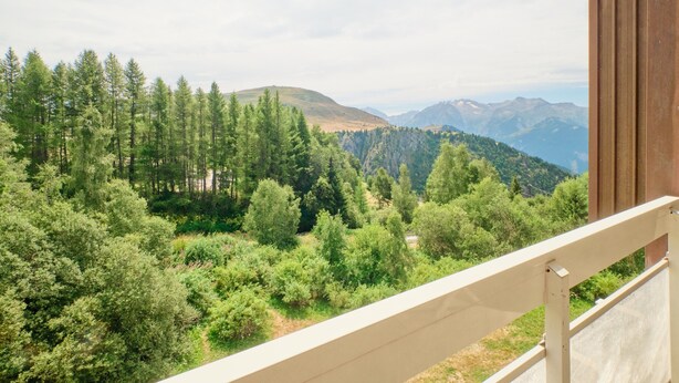 A balcony with a view of a forested mountain landscape. - Apartment 'Appartement Alpe D'huez' with Balcony (Huez)