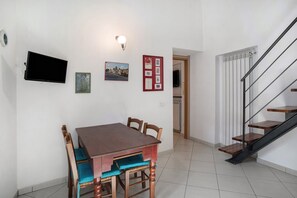 A dining area with a table and chairs, a flat-screen TV mounted on the wall, and a staircase with wooden steps. - Apartment 'Loft Nel Centro Di Alassio' with Wi-Fi and Air Conditioning (Alassio)