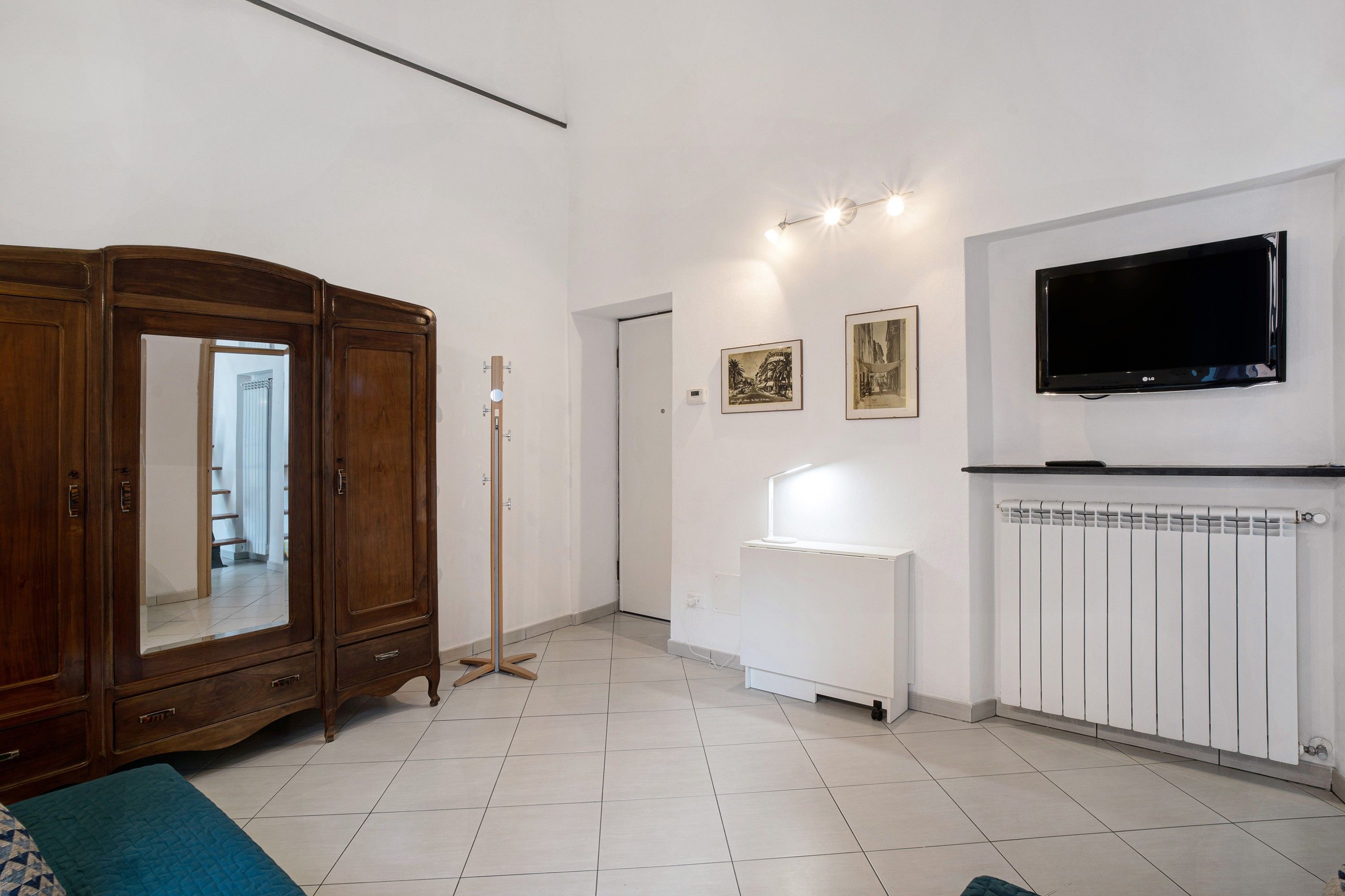 Une pièce comprenant une grande armoire en bois, un téléviseur à écran plat fixé au mur et un radiateur.