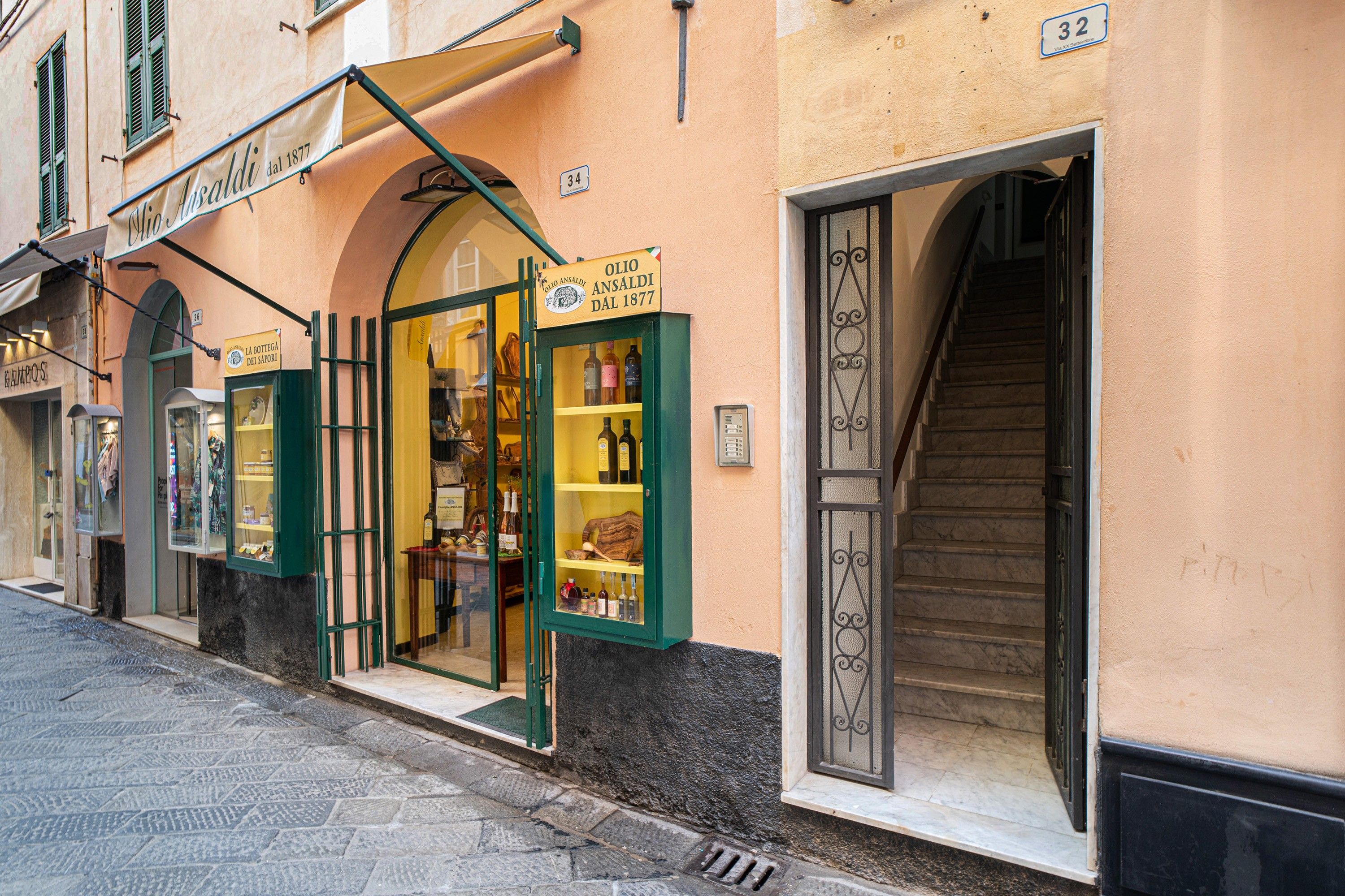 A storefront with a sign reading 'OLIO ANSALDI dal 1877' and a display case with various bottles.