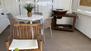 Un coin repas avec une table ronde, des chaises, une petite plante et un banc en bois.