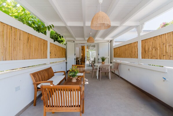 A covered outdoor area with wooden furniture, a hanging light fixture, and vertical greenery.