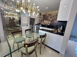 Una cocina moderna con una mesa de comedor de vidrio, sillas de madera y un refrigerador de acero inoxidable.