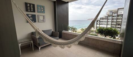 Ein Balkon mit einer Hängematte, einer Couch und einem kleinen Tisch.