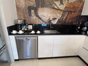 Una cocina moderna con lavavajillas, cafetera y una gran obra de arte de mosaico sobre el mostrador.
