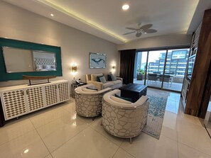 Una sala de estar moderna con un sofá, dos sillones, una mesa de centro, un televisor y un ventilador de techo.