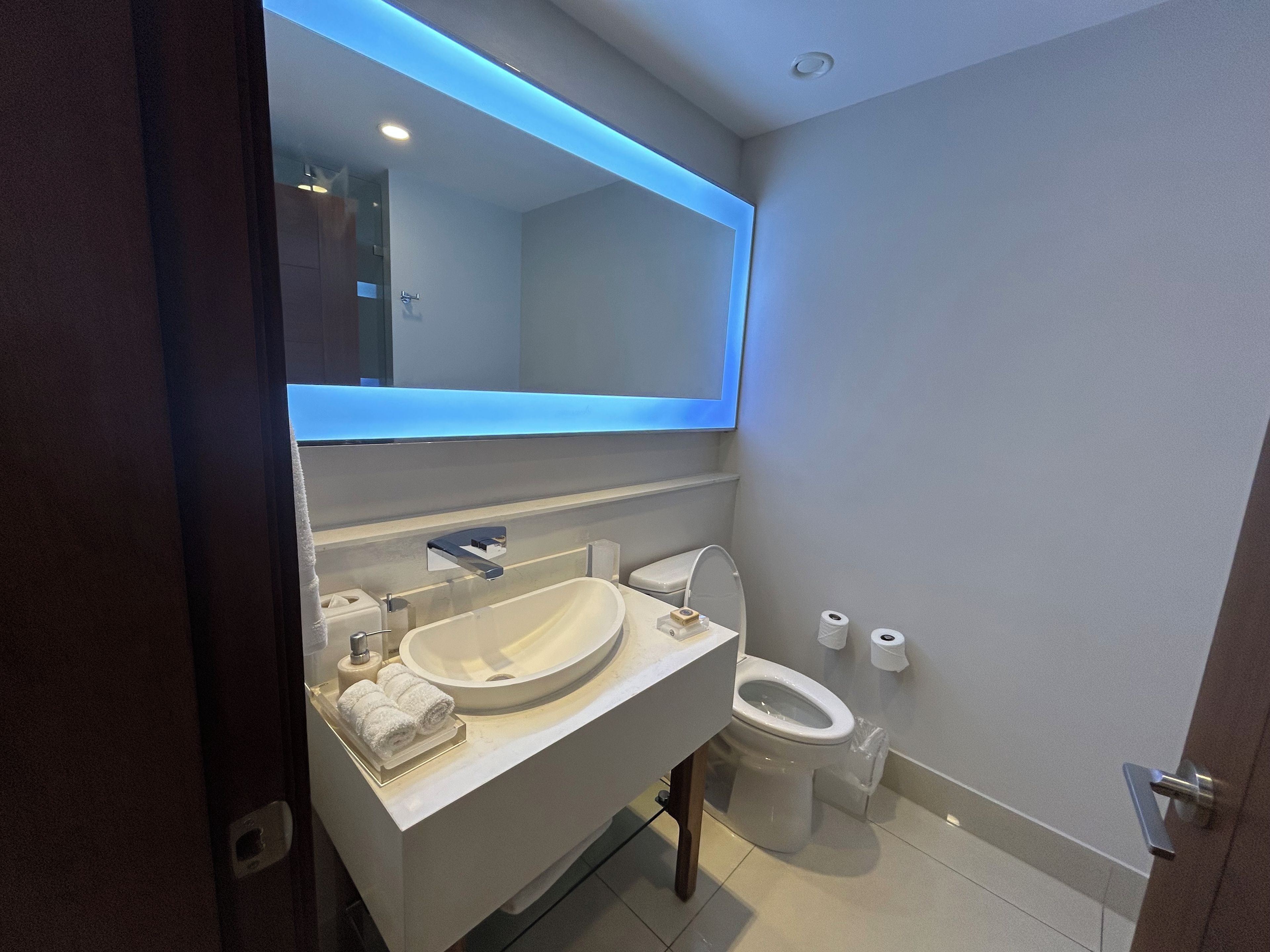 Un baño moderno con un espejo grande, un lavabo y un inodoro.