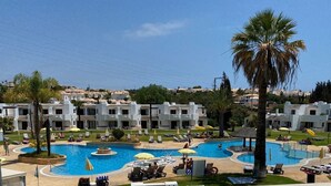 A resort with multiple swimming pools, sun loungers, and palm trees.
