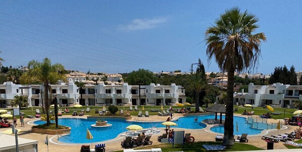 A resort with multiple swimming pools, sun loungers, and palm trees.