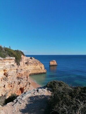 Paisagem costeira com falésias rochosas e mar azul cristalino.