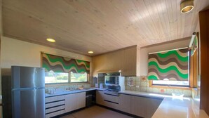 A kitchen with wooden cabinets, a refrigerator, an oven, and a microwave. - A perfect view of Gabo Island. (Mallacoota)