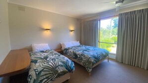 A hotel room with two beds, a ceiling fan, and a window with curtains. - A perfect view of Gabo Island. (Mallacoota)
