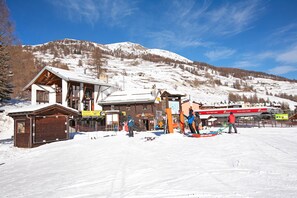 A ski resort with a wooden lodge, ski rental area, and a mountain backdrop.