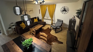 A cozy living room with a sofa, a wooden dining table, a dog, and a ceiling light fixture. - Prime Lodge - Koblenz (Koblenz)