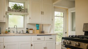 A kitchen with white cabinets, a stove, and a window with a 'Welcome' sign above the sink.