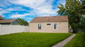 A single-story house with a paved driveway and a white fence.