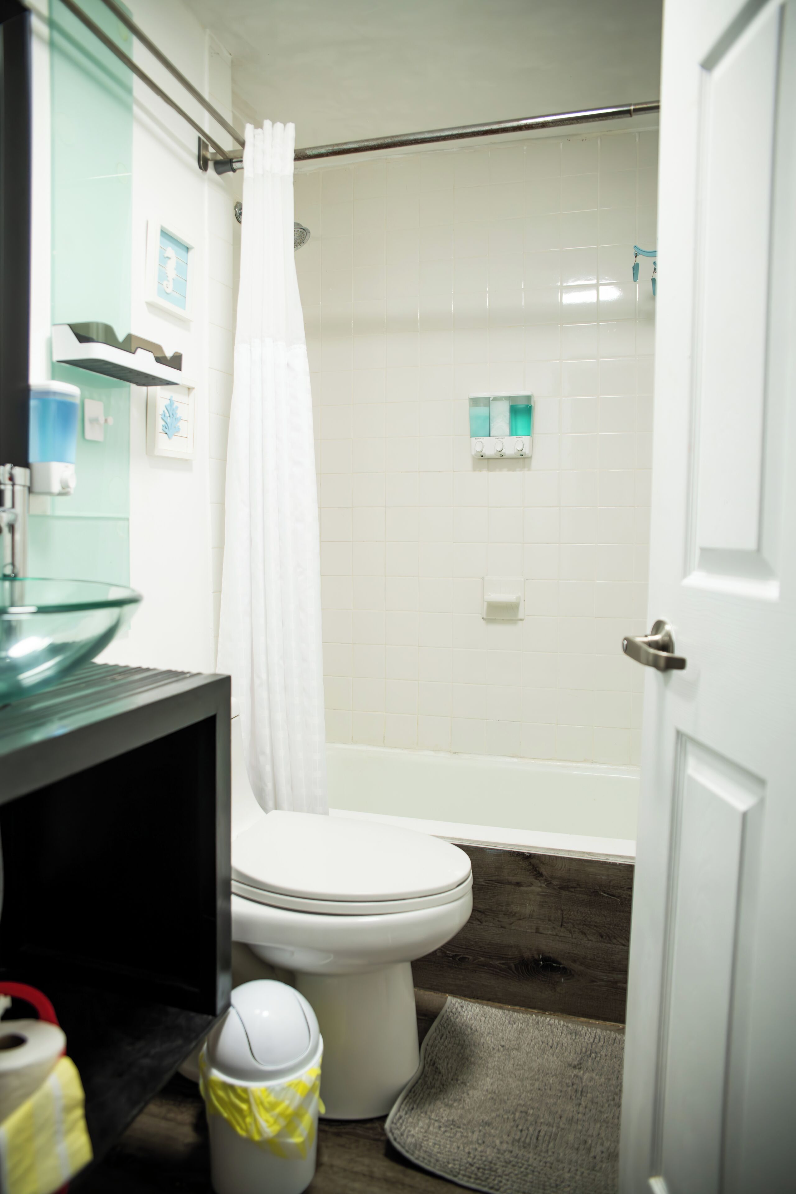 A bathroom with a glass sink, toilet, and shower curtain.