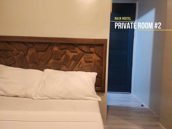 A private room with a wooden headboard and white bedding.